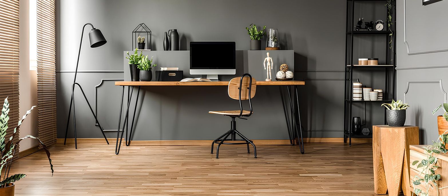 Moderner Arbeitsplatz mit Holzschreibtisch, Computer, Bürostuhl, Stehlampe und Regalen in einem grauen Raum.